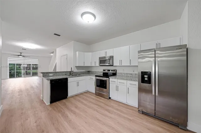 a kitchen with granite countertop a refrigerator and a stove top oven