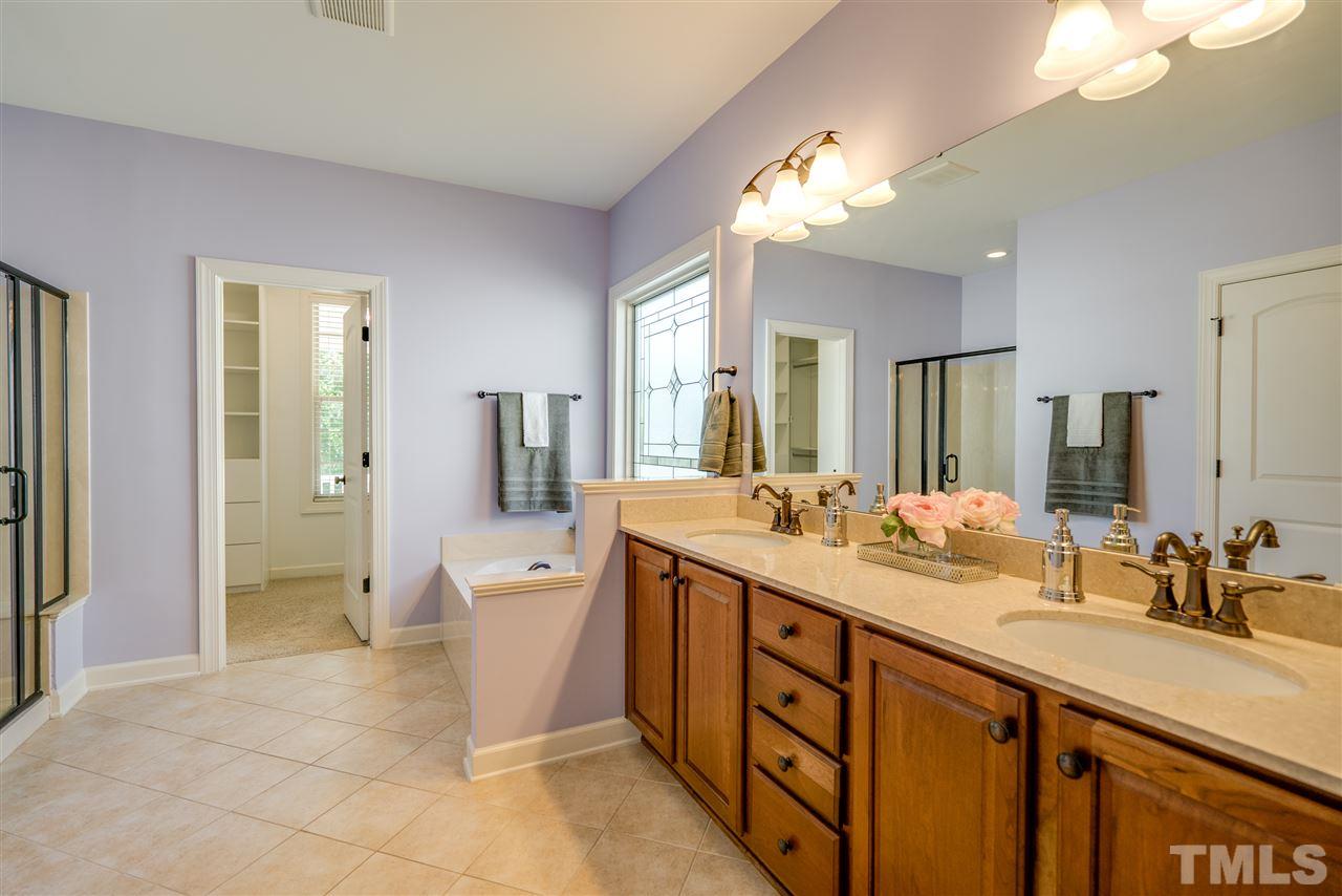 1016 Vino Drive Raleigh, NC 27607 - Photo 15 of 25 a spacious bathroom with a double vanity sink a large mirror and a shower