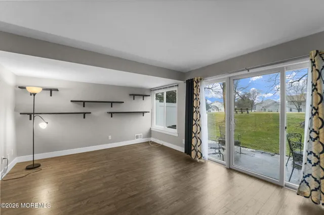 a view of empty room with wooden floor and floor to ceiling window