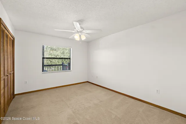 an empty room with closet and a chandelier fan