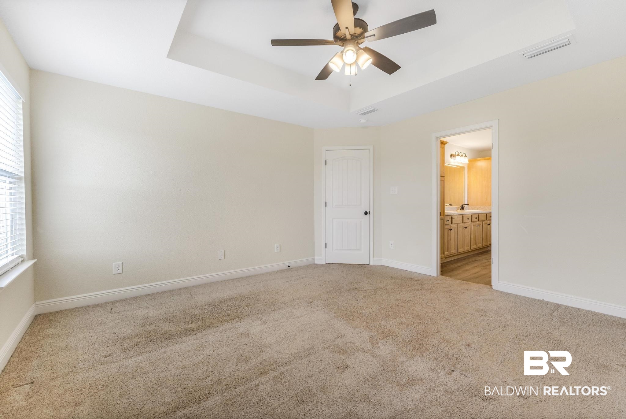 21580 Talbot Lane Robertsdale, AL 36567 - Photo 17 of 25 Unfurnished bedroom featuring a tray ceiling, light colored carpet, ceiling fan, and ensuite bath