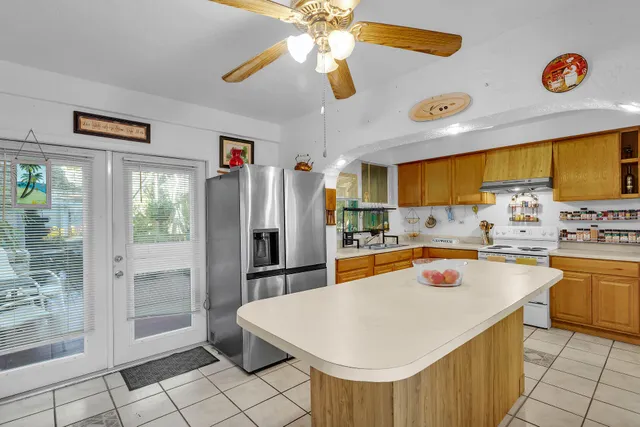 a kitchen with stainless steel appliances a white refrigerator a oven a sink with a dining table and chairs