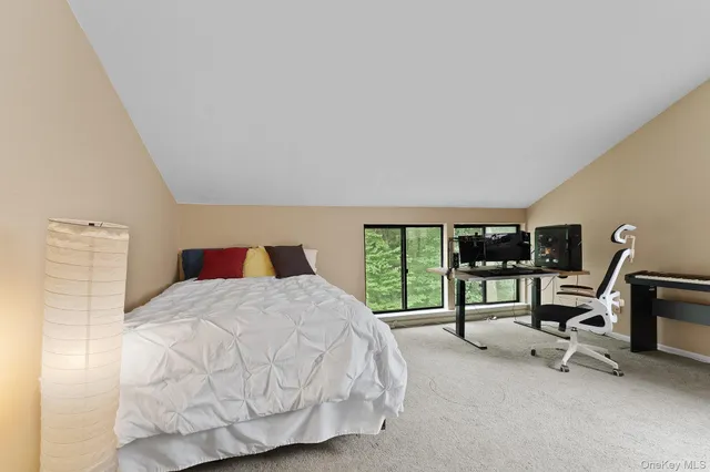 a bedroom with a bed a large window with table and chair