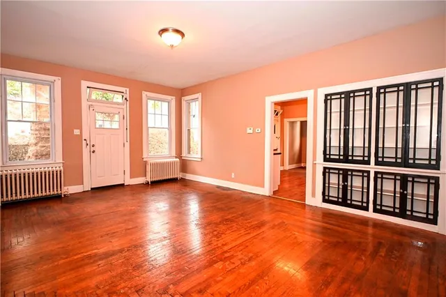 an empty room with wooden floor and windows