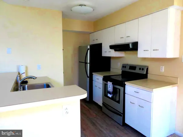 a kitchen with stainless steel appliances a stove a refrigerator a sink and white cabinets