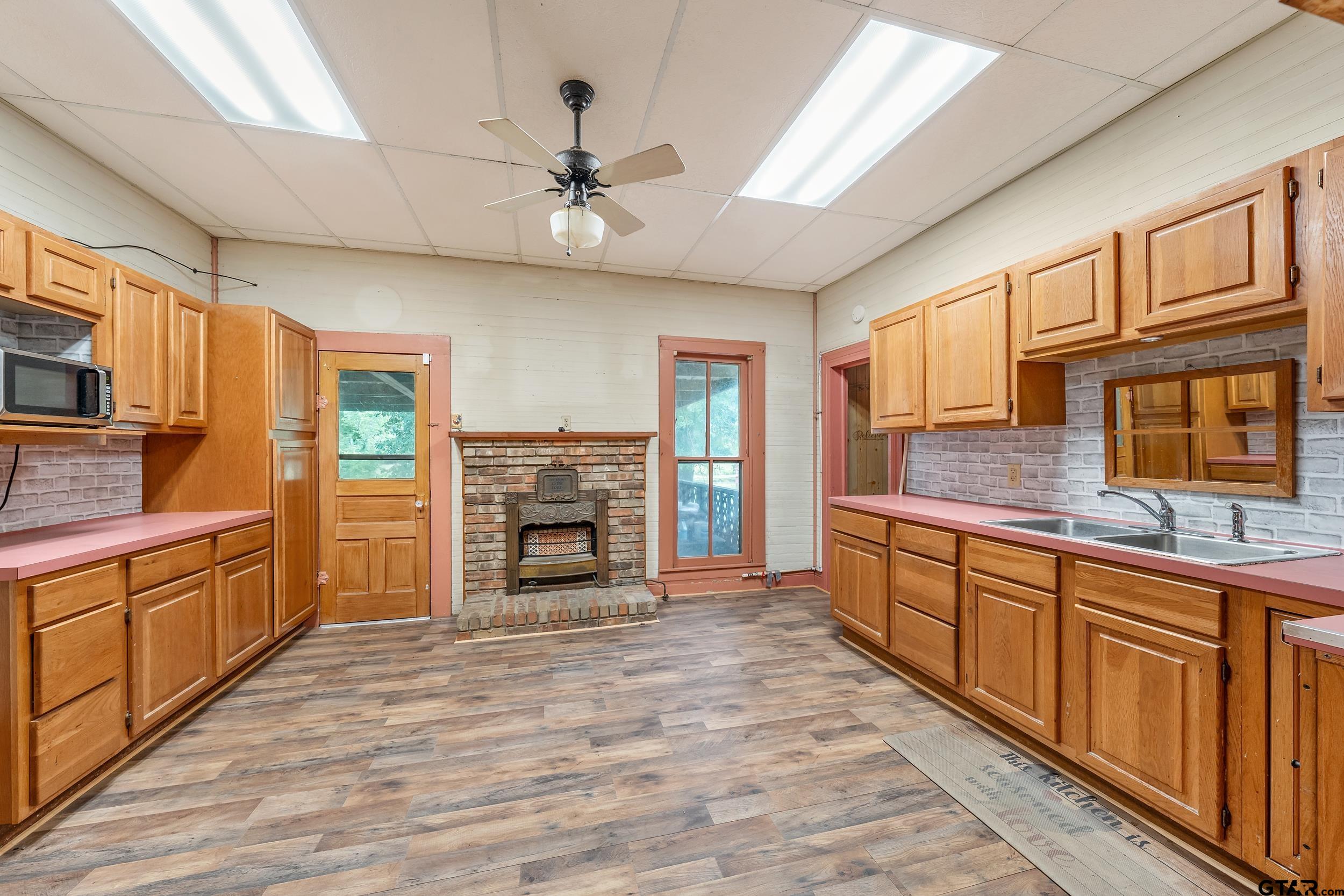 2888 Farm To Market Road 999 Gary, TX 75643 - Photo 12 of 46 a large kitchen with stainless steel appliances granite countertop a stove top oven a sink dishwasher a dining table and chairs with wooden floor