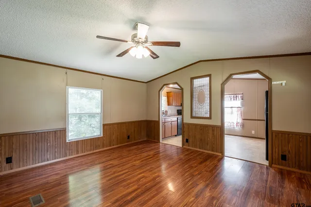 a view of empty room with wooden floor and fan