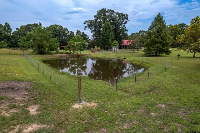 a view of a lake with a yard and large trees