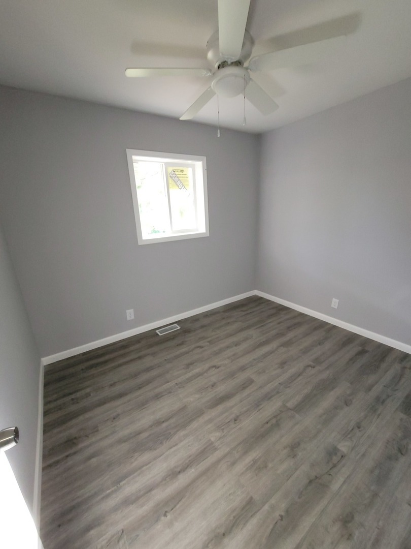 133 Kingston Road Bolingbrook, IL 60440 - Photo 10 of 19 an empty room with wooden floor fan and windows