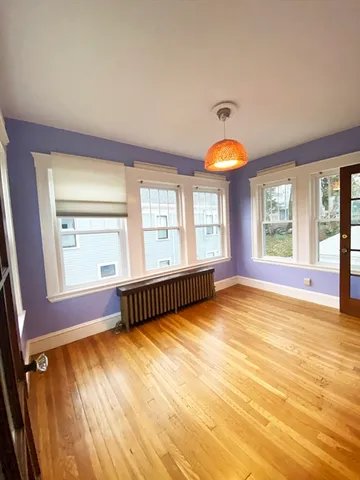a view of an empty room with window and wooden floor