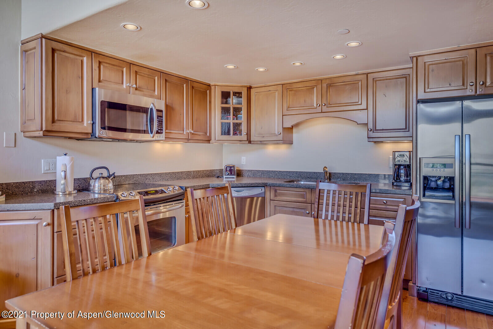 400 Wood Road, Unit 2302 Snowmass Village, CO 81615 - Photo 7 of 16 a kitchen with stainless steel appliances granite countertop a stove a sink a microwave a dining table and chairs