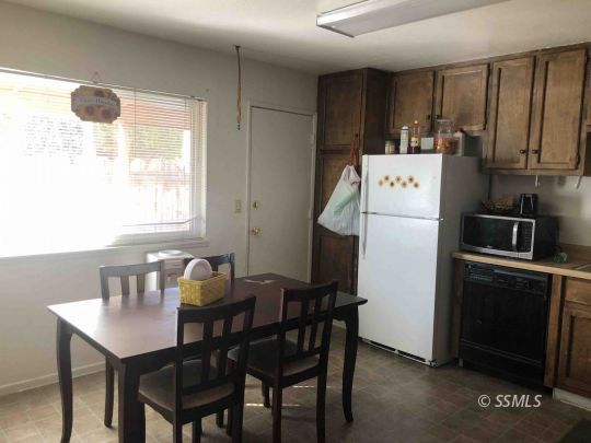 125 South Broadway Street Ridgecrest, CA 93555 - Photo 20 of 24 a utility room with stainless steel appliances a table chairs and a refrigerator
