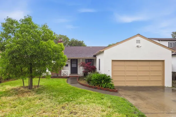 a front view of a house with a yard and trees
