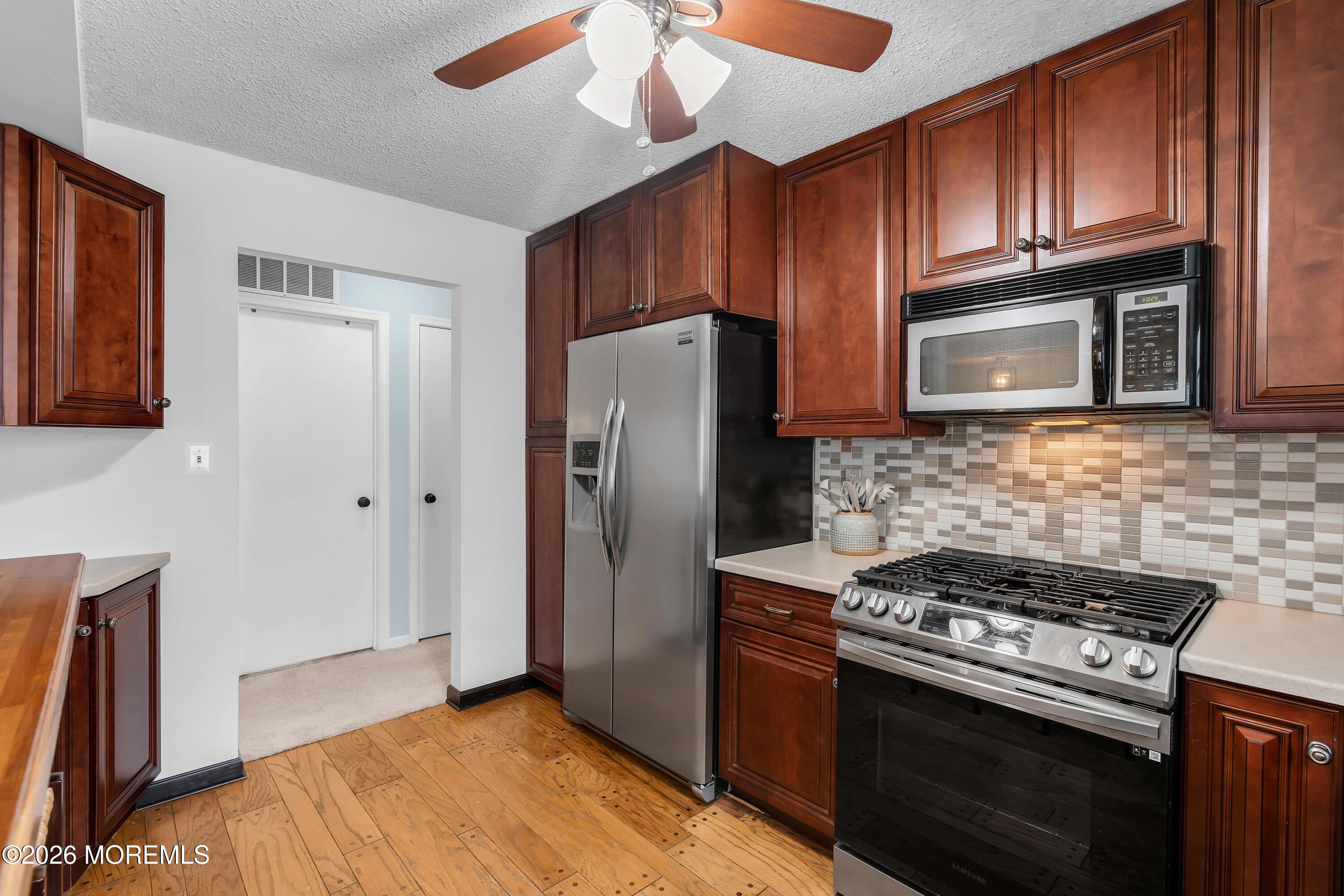 129 Tulip Lane Freehold, NJ 07728 - Photo 10 of 25 a kitchen with granite countertop wooden cabinets and stainless steel appliances
