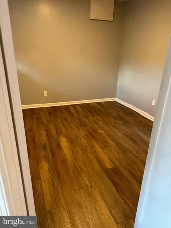 a view of an empty room with wooden floor and closet