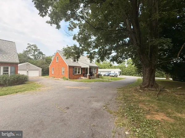 a front view of a house with a yard and large trees