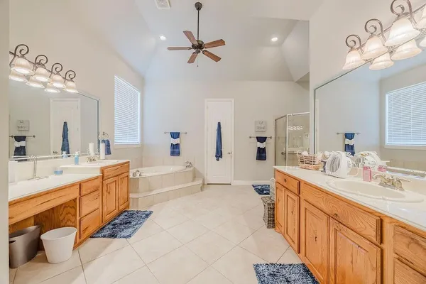 a large white bathroom with a double vanity sink a mirror a bathtub and a shower