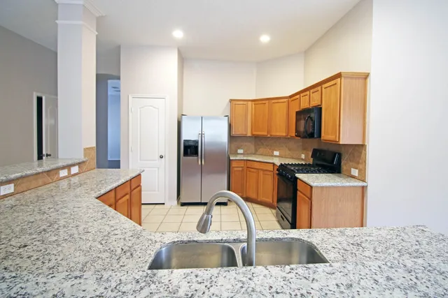 a kitchen with stainless steel appliances granite countertop a sink a stove and a refrigerator