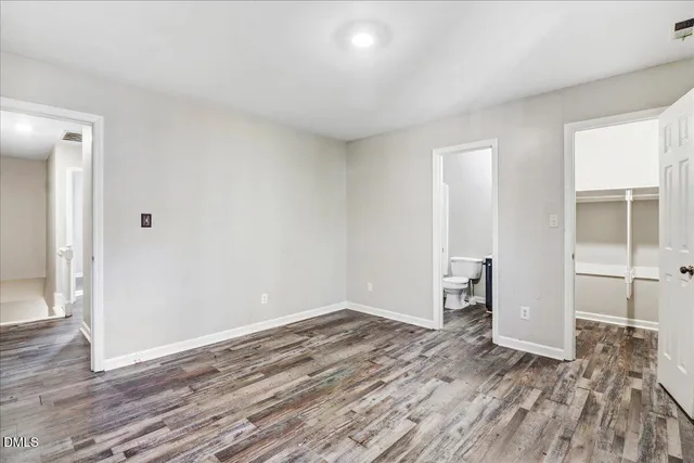 a view of an empty room with wooden floor and closet