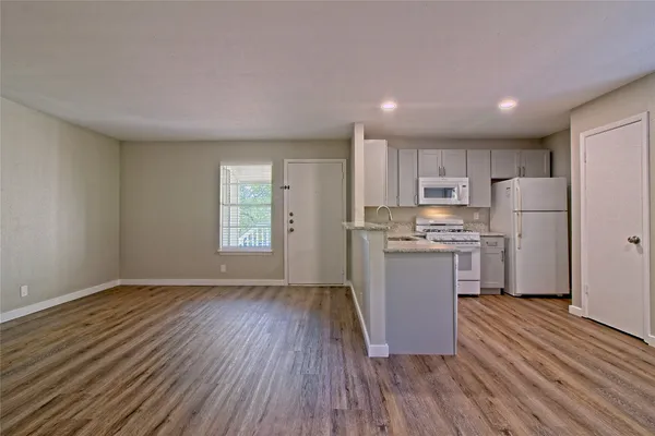 a kitchen with a refrigerator and wooden floor