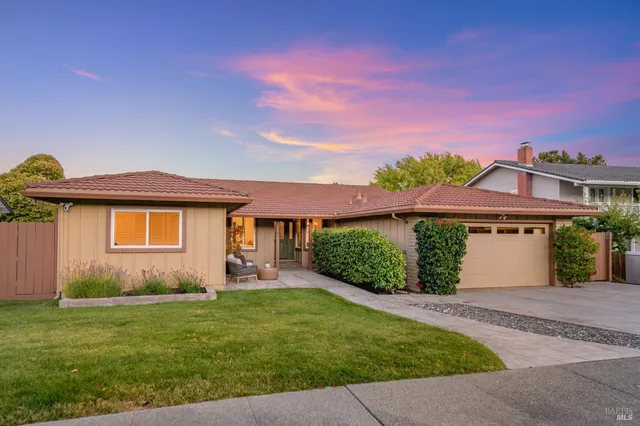 a front view of a house with a yard and potted plants