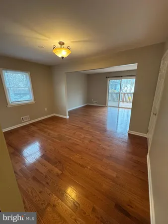 a view of an empty room with window and wooden floor