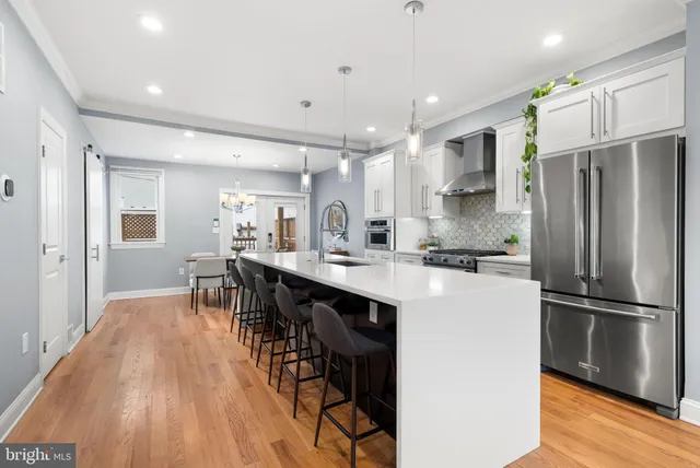 a kitchen with stainless steel appliances a refrigerator a sink dishwasher a stove and a oven with wooden floor