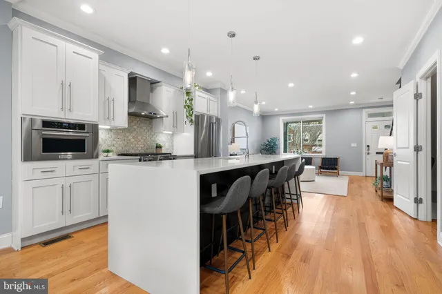 a kitchen with stainless steel appliances kitchen island granite countertop a stove top oven a sink a dining table and chairs with wooden floor