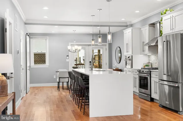 a kitchen with stainless steel appliances a refrigerator a stove a sink dishwasher and white cabinets with wooden floor