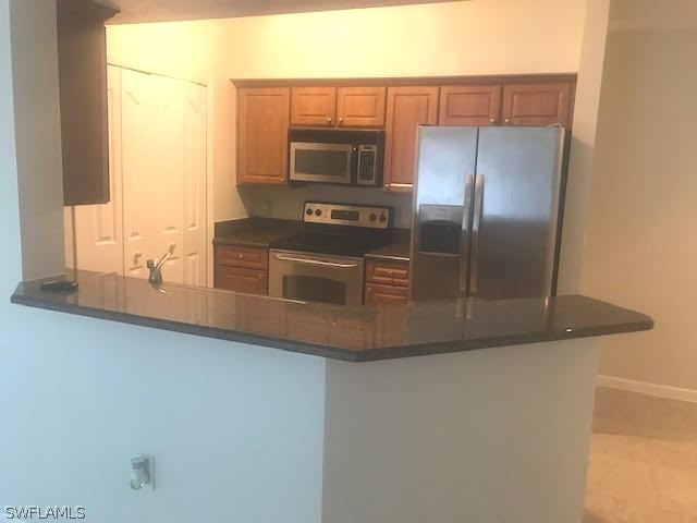 13010 Positano Circle, Unit 101 Naples, FL 34105 - Photo 2 of 26 a kitchen with granite countertop a refrigerator and a stove