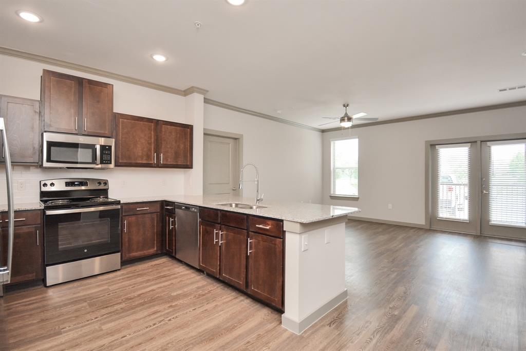 a large kitchen with wooden floors and stainless steel appliances