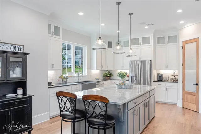 a kitchen with stainless steel appliances granite countertop a stove a sink dishwasher a dining table and chairs with wooden floor