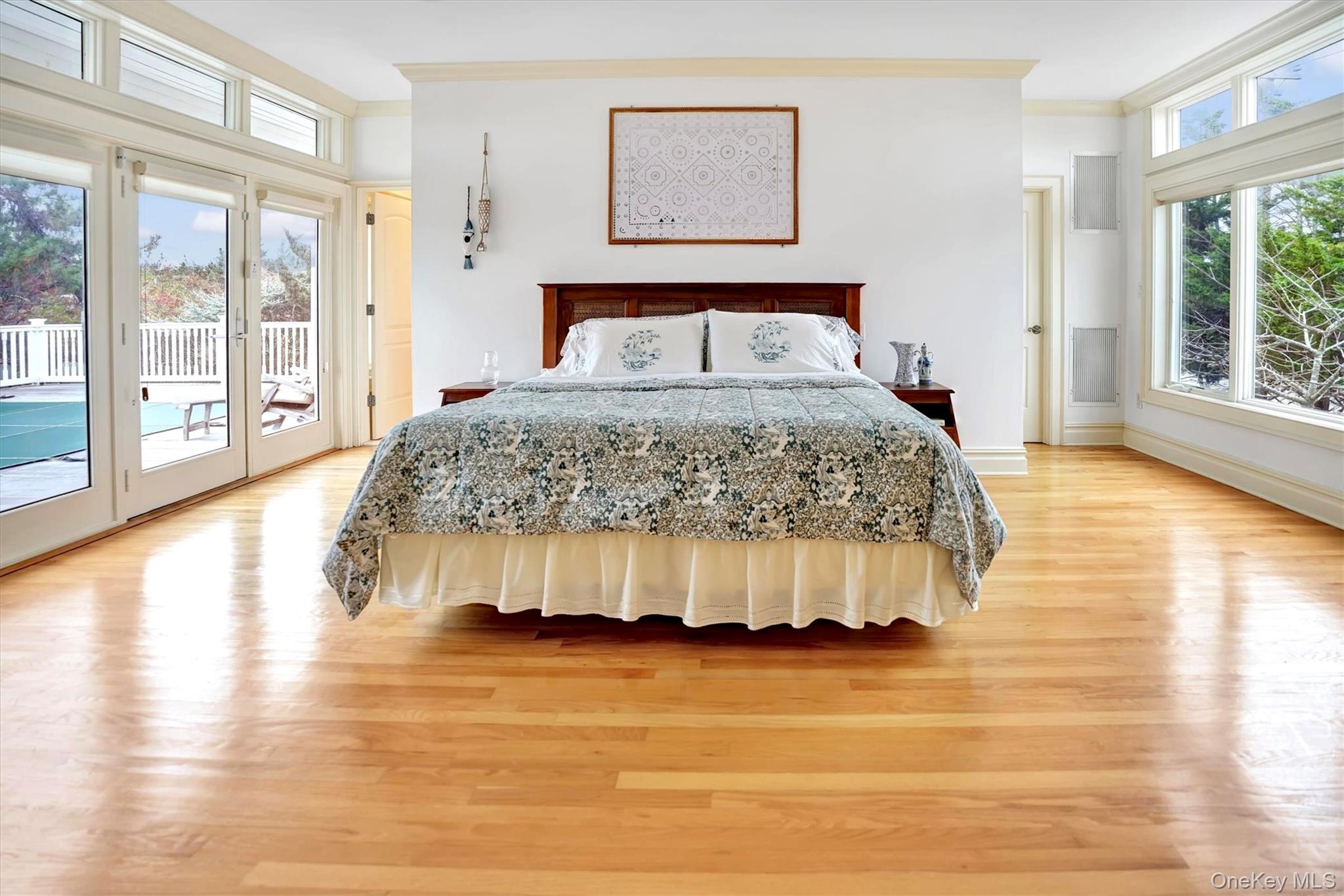 605 Dune Road Westhampton, NY 11978 - Photo 17 of 44 First Floor Primary Bedroom with French Doors to Pool & amazing Bay views. There are wood finished floors, and crown molding.