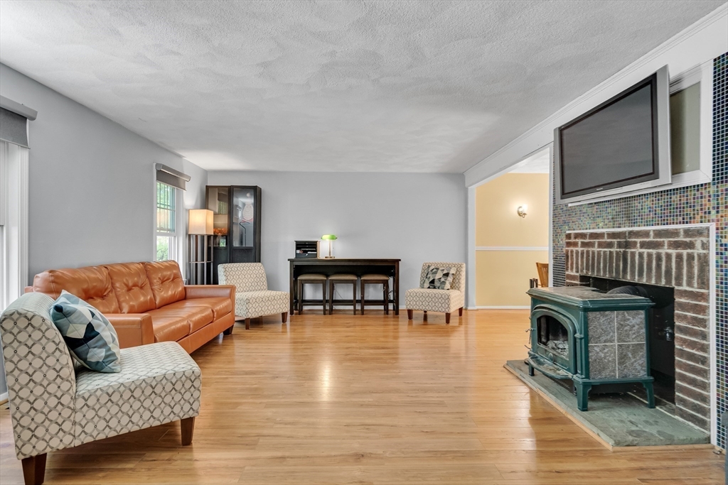58 MacIntosh Lane, Unit 58 Boxborough, MA 01719 - Photo 9 of 23 a living room with furniture a fireplace a flat screen tv and kitchen view