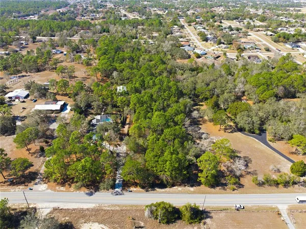 an aerial view of residential houses with outdoor space and trees
