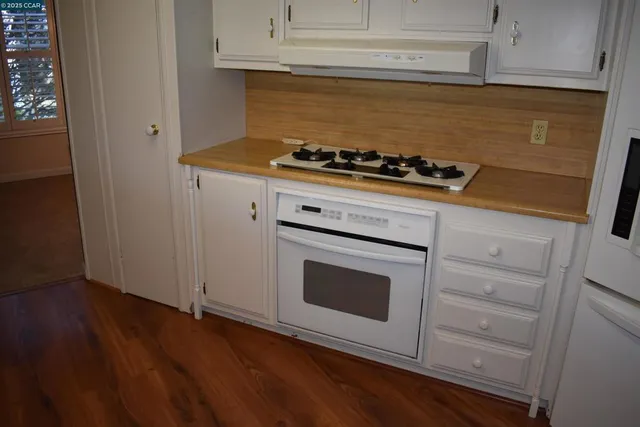 a kitchen with granite countertop cabinets and stove top oven