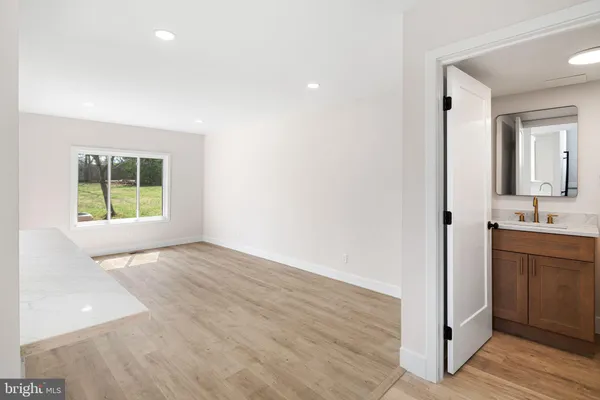 a view of an empty room with a window and kitchen view