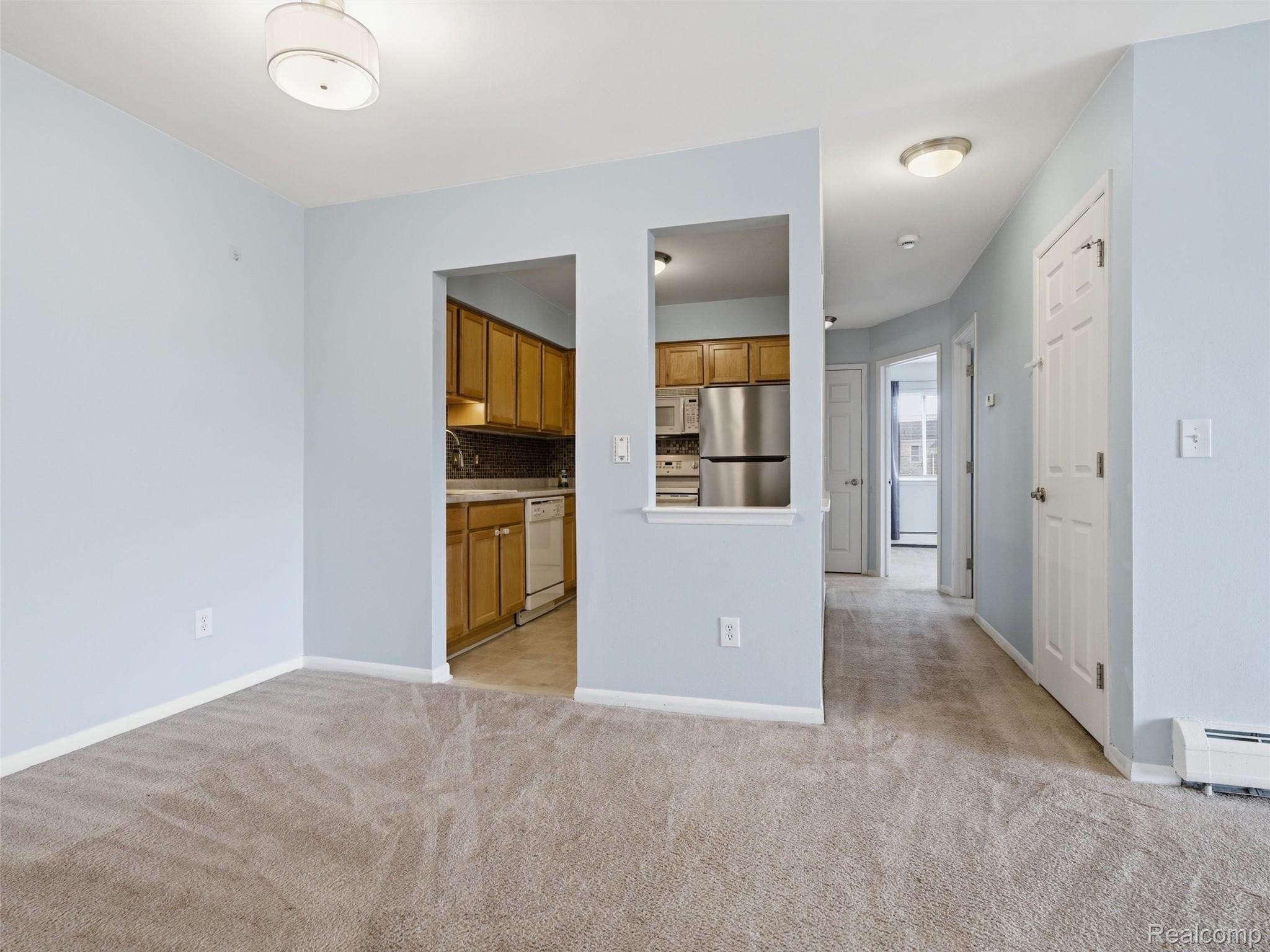 475 Baldwin Avenue, Unit 26 Rochester, MI 48307 - Photo 10 of 19 Kitchen with white appliances, wood finish cabinetry, backsplash, light countertops, and light carpet