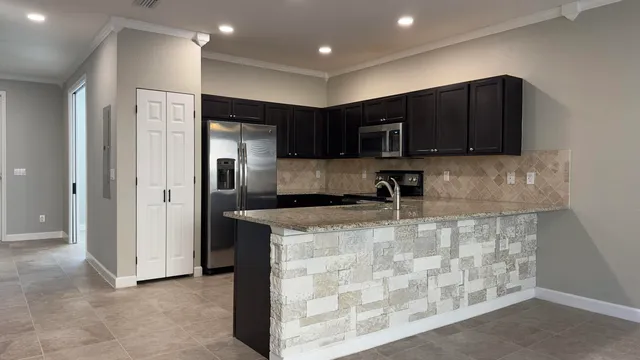 a kitchen with stainless steel appliances granite countertop a refrigerator and a stove top oven