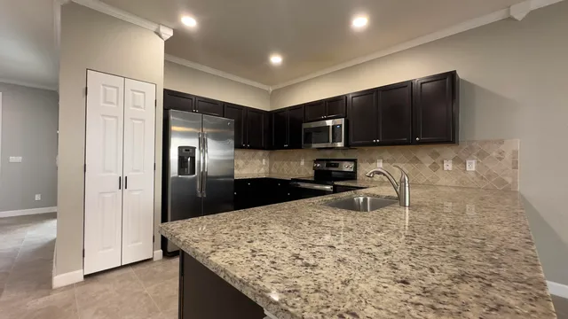 a kitchen with stainless steel appliances granite countertop a sink stove and refrigerator