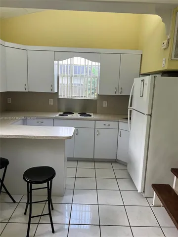 a kitchen with a sink a refrigerator and cabinets