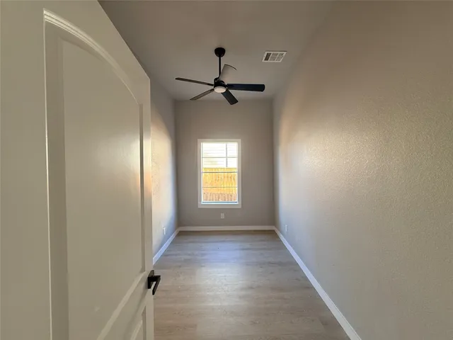 a view of empty room with wooden floor and fan