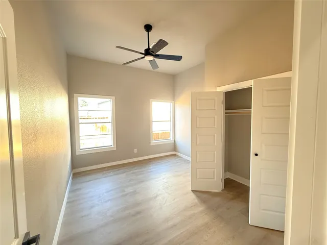 a view of empty room with wooden floor and fan
