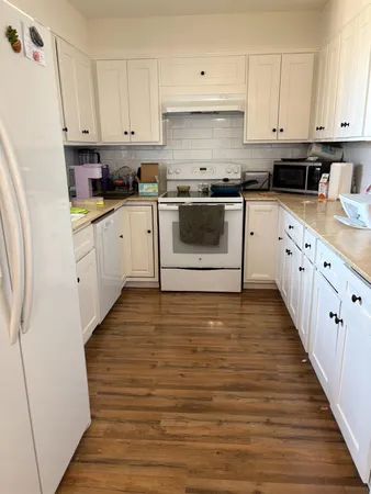 a kitchen with granite countertop white cabinets and white appliances