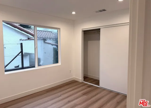 an empty room with wooden floor and a ceiling fan
