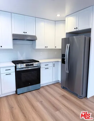 a kitchen with stainless steel appliances granite countertop a refrigerator stove and white cabinets