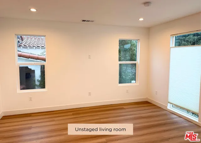 a view of an empty room with wooden floor and a window