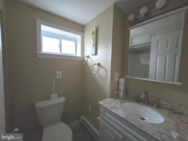 a bathroom with a granite countertop toilet a sink and mirror