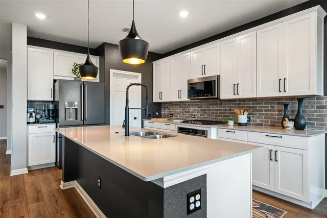 a kitchen with stainless steel appliances granite countertop a sink a stove and a refrigerator