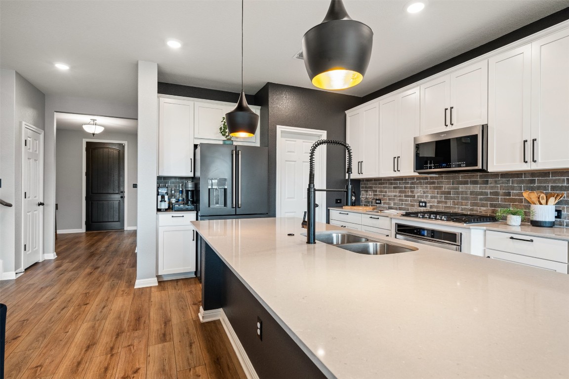 1009 Dog Iron Street Georgetown, TX 78633 - Photo 15 of 39 a kitchen with stainless steel appliances a center island wooden floor and a refrigerator